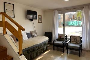 a bedroom with a bed and two chairs and a staircase at Copos de Nieve in El Bolsón