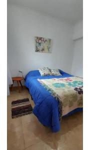 a bed with a blue comforter in a room at Departamento Interno 1 in Santo Tomé