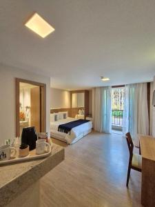 ドミンゴス・マルチンスにあるApart Vista Azul - Conforto com a vista para a mata de pinheirosのベッドとテーブルが備わる広いホテルルームです。