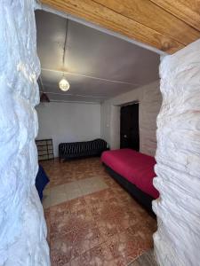a bedroom with a red bed and a stone wall at Nativo Atacama in San Pedro de Atacama +2 photos