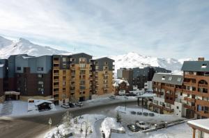 eine Stadt mit Gebäuden und schneebedeckten Bergen in der Unterkunft Joker Appartements VTI in Val Thorens