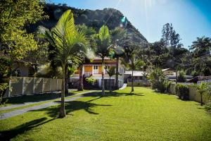 a yard with palm trees in front of a house at Chácara no centro para até 15 pessoas com piscina aquecida e 5 quartos in Duas Barras