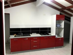 eine Küche mit roten Schränken und einer Spüle in der Unterkunft Ambre des iles in Sainte-Anne