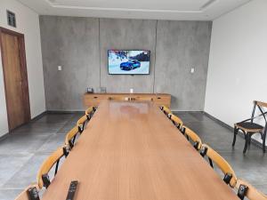 einen Konferenzraum mit einem großen Holztisch und einem TV in der Unterkunft Saltos Luxury - Quincho & Piscina in Salto del Guairá