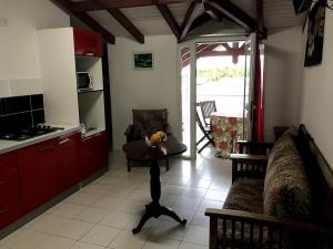 Eine Küche mit einer Couch und einem Tisch, auf dem ein Hund sitzt. in der Unterkunft Ambre des iles in Sainte-Anne