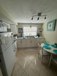 eine Küche mit einem weißen Kühlschrank und einem Tisch in der Unterkunft Cozy Beach Rental 1B/1B in St Pete Beach