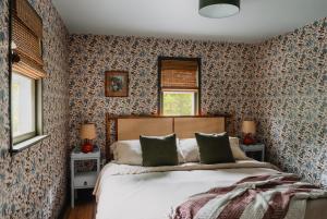 - une chambre avec un grand lit et du papier peint floral dans l'établissement Roebling House 1850s Cabin Hot Tub Fire Pit, à Lackawaxen