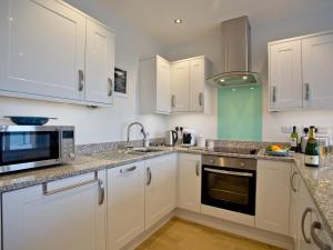 eine Küche mit weißen Schränken und einer Spüle in der Unterkunft Curlew 4 - The Cove in Brixham + 9 Fotos