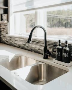 eine Küchenspüle mit zwei schwarzen Flaschen darauf in der Unterkunft Swan Pond Cabin Hot Tub & Firepit Retreat in Swan Lake + 40 Fotos