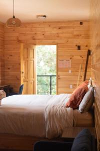 ein Schlafzimmer mit einem Bett in einer Holzwand in der Unterkunft San José del Pacífico- Cabañas Camino al Cielo 1 in San Mateo Río Hondo