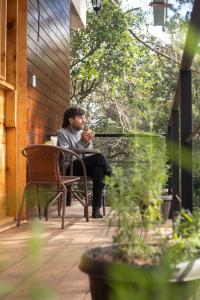 Ein Mann, der auf einer Bank auf einer Veranda sitzt. in der Unterkunft San José del Pacífico- Cabañas Camino al Cielo 1 in San Mateo Río Hondo + 12 Fotos