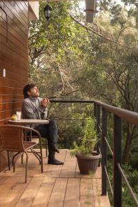 Ein Mann, der an einem Tisch auf einem Deck sitzt. in der Unterkunft San José del Pacífico- Cabañas Camino al Cielo 1 in San Mateo Río Hondo
