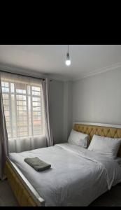 Un dormitorio con una cama blanca con una ventana. en The Nest, en Thika