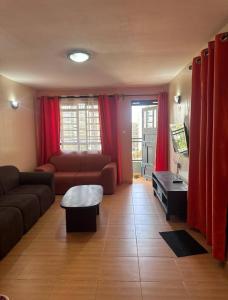 sala de estar con cortinas rojas y sofá en The Nest, en Thika