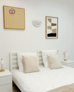 ein weißes Bett mit weißen Kissen im Schlafzimmer in der Unterkunft Le Tiny Strasbourg - Adorable logement calme en plein coeur de la ville in Straßburg