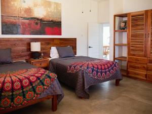 ein Schlafzimmer mit zwei Betten und einem Gemälde an der Wand in der Unterkunft Beachfront villa with pool and staff in Treasure Beach + 46 Fotos