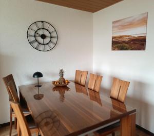 a dining room table with chairs and a clock on the wall at Casa del Norte in Brackenheim