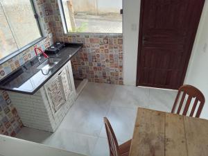 eine Küche mit einem Waschbecken, einem Tisch und einem Fenster in der Unterkunft Casa Verde Guest in Saco de Fora