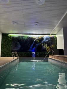 a swimming pool in a building with a painting on the wall at Hotel Onix in Viseu