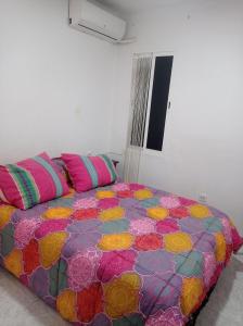 Bett mit farbenfroher Bettdecke in einem Zimmer in der Unterkunft Valencia 2 en piso familiar in Valencia