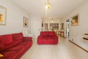 un soggiorno con un divano rosso e un tavolo di Edifício Sunshine Guarujá - Apto Alto Padrão Próximo à Praia a Guarujá