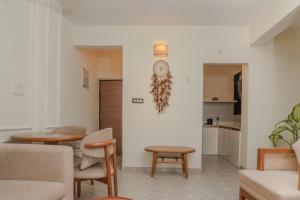 a living room with a table and a clock on the wall at Botanica Luxury 1BHK Apartment, Pool & Parking - Near Candolim Beach in Candolim