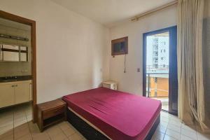 una camera con letto rosa in una stanza con finestra di Edifício Sunshine Guarujá - Apto Alto Padrão Próximo à Praia a Guarujá