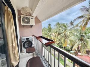 balcón con lavadora y palmeras en Modern Studio with Pool Access Near Candolim Beach - Balcony & Kitchenette, en Candolim