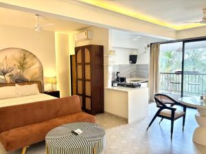 Una sala de estar con una cama y una cocina. en Modern Studio with Pool Access Near Candolim Beach - Balcony & Kitchenette, en Candolim