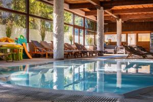 a swimming pool in a house with chairs and tables at Hotel Slovan in Tatranská Lomnica