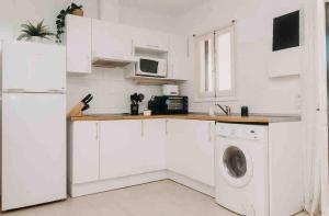 eine weiße Küche mit einer Waschmaschine und einer Waschmaschine in der Unterkunft Espectacular Apartamento in Cala'n Bosch