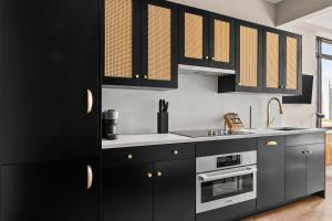 Una cocina con gabinetes negros y electrodomésticos de acero inoxidable en Freeman 903 by Rove 1BR Condo with Shared Amenities, en Nueva York