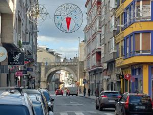 eine Stadtstraße mit auf der Straße geparkten Autos und einer Brücke in der Unterkunft Apartamento Puerta de San Fernando in Lugo