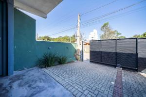 a green building with a gate and a brick patio at Casa em Bombinhas in Bombinhas