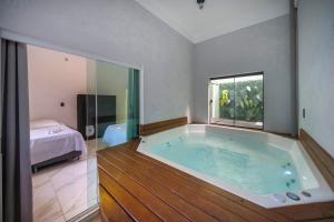 a large bath tub in a room with a bedroom at Casa em Bombinhas in Bombinhas