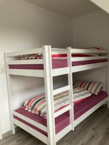 2 weiße Etagenbetten in einem Zimmer in der Unterkunft Ostfrieslandsuite in Aurich + 19 Fotos