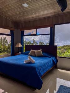 a bedroom with a blue bed with large windows at Cabaña Elvira in La Cruz