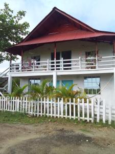 a white house with a fence in front of it at Apart Cabaña KTIK in San Bernardo del Viento