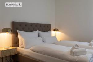 - une chambre avec 2 lits avec des draps blancs et 2 lampes dans l'établissement ღLiboria I Aidling Panorama Stilvolles Ferienhaus mit Bergblick, à Riegsee 2 autres photos