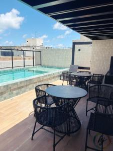 a patio with tables and chairs and a swimming pool at Mares 502 in Tambaú +5 photos