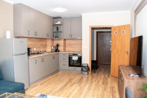 een keuken met witte kasten, houten vloeren en een koelkast bij Gondola Apartments Lux in Bansko