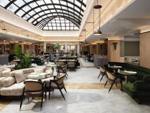 Un restaurante con mesas y sillas y un techo de cristal. en Mandarin Oriental, Vienna, en Viena