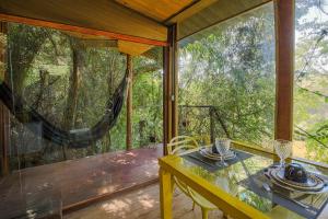 eine abgeschirmte Veranda mit einem Tisch und einer Hängematte in der Unterkunft Casa de Vidro na Mata há 90km de São Paulo, com Lago, Piscina, Caiaque, Stand UP, Cascata e Escorrega no Lago - Quinta do Vale Itatiba in Itatiba