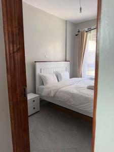 ein Schlafzimmer mit einem Bett mit weißen Laken und einem Fenster in der Unterkunft One Bedroom Apartment near KSG - Arc II in Nairobi