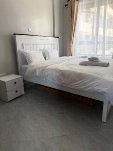 ein Schlafzimmer mit einem Bett mit weißen Laken und einem Fenster in der Unterkunft One Bedroom Apartment near KSG - Arc II in Nairobi