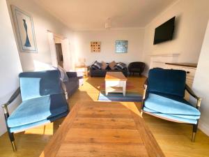 ein Wohnzimmer mit zwei blauen Stühlen und einem Sofa in der Unterkunft 1 Belmont Court in Woolacombe