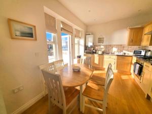 eine Küche mit einem Holztisch und Stühlen in einem Zimmer in der Unterkunft 1 Belmont Court in Woolacombe