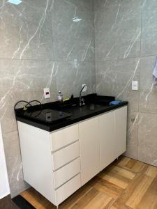 a bathroom with a sink and a marble wall at Loft 1 Elegante e Aconchegante Airport GRU in Guarulhos