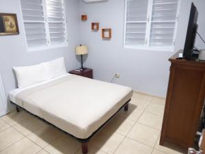 um quarto com uma cama com lençóis brancos e janelas em Casa Isla Azul, 4BR-3Ba-2Kit Wi-Fi, AC, Pool, Solar Power Boqueron Puerto Rico Walk to El Poblado Cabo Rojo em Cabo Rojo mais 61 fotografias