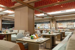 ein Restaurant mit Tischen und Stühlen in einem Raum in der Unterkunft InterContinental Hotels Zhengzhou in Zhengzhou